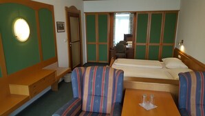 Et lille hotelværelse med seng, skrivebord, stol og sofa.