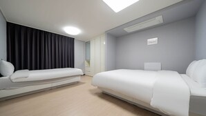 Ein modernes Hotelzimmer mit einem großen Bett, einer kleinen Sitzecke, einem Schreibtisch und einem Kleiderschrank.
