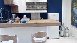 A modern kitchen with a wooden countertop, white cabinets, and a built-in espresso machine. - Luxury studio suite in artist Villa with sea view (Eze)