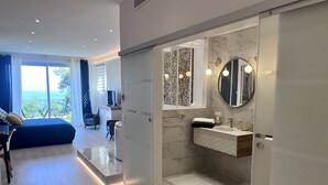 A modern bathroom with a marble sink, a round mirror, and a glass-enclosed shower. - Luxury studio suite in artist Villa with sea view (Eze)
