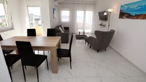 Ein modernes Wohnzimmer mit Essbereich, einer Couch, einem Fernseher und einem Gemälde an der Wand.