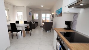 Eine moderne Küche mit Essbereich, Blick ins Freie und einem an der Wand befestigten Flachbildfernseher.