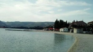 Eine Küstenlandschaft mit Sandstrand, ruhiger See und Gebäuden im Hintergrund.