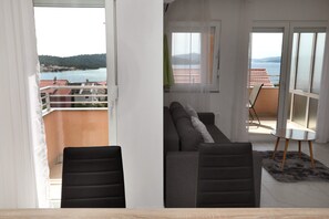 Un balcon donnant sur un plan dâeau et des collines, un canapĂ©, des fauteuils et une petite table.