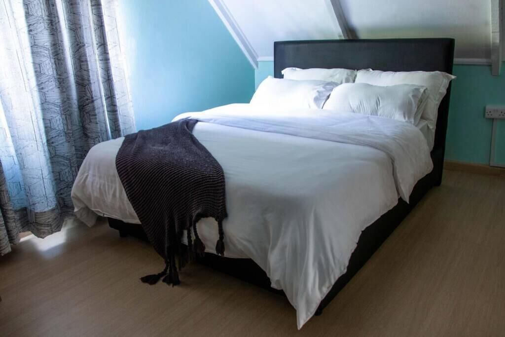 A bedroom with a bed, curtains, and a window.