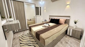 A modern bedroom with a bed, bedside tables, a mirror, and an air conditioning unit.
