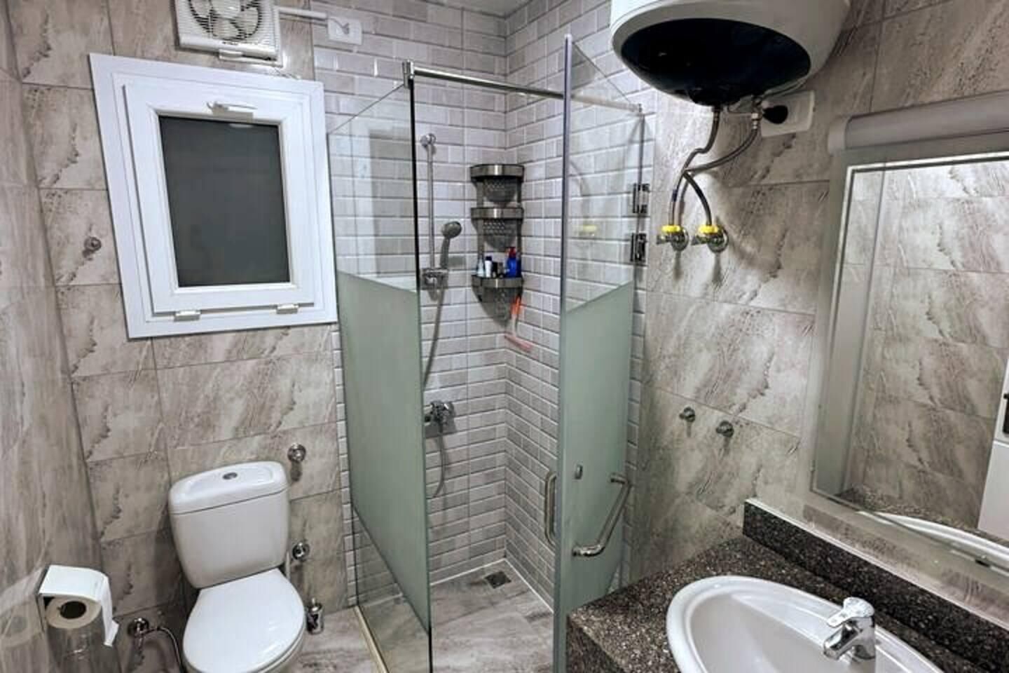 A bathroom with a toilet, a glass-enclosed shower, and a sink.
