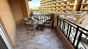 A balcony with wicker furniture and a tiled floor, overlooking a residential area with multiple apartment buildings.