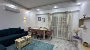 A modern living room with a sofa, coffee table, dining table, and chairs.
