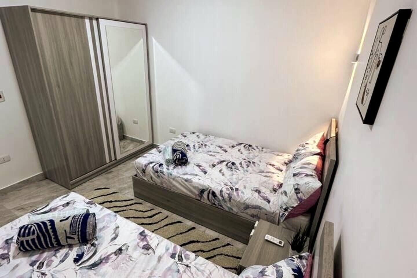 A small bedroom with a bed, a wardrobe, and a mirror.