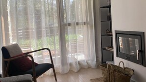 A living room with a large window, a chair, a TV, and a bookshelf.