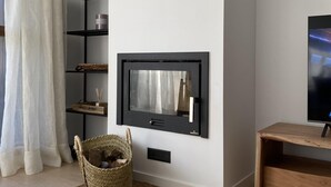 A modern living room with a mounted TV, wooden shelves, a wicker basket, and a wooden side table.