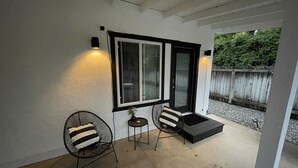 Una veranda riparata con due sedie, un tavolino e una panca nera.