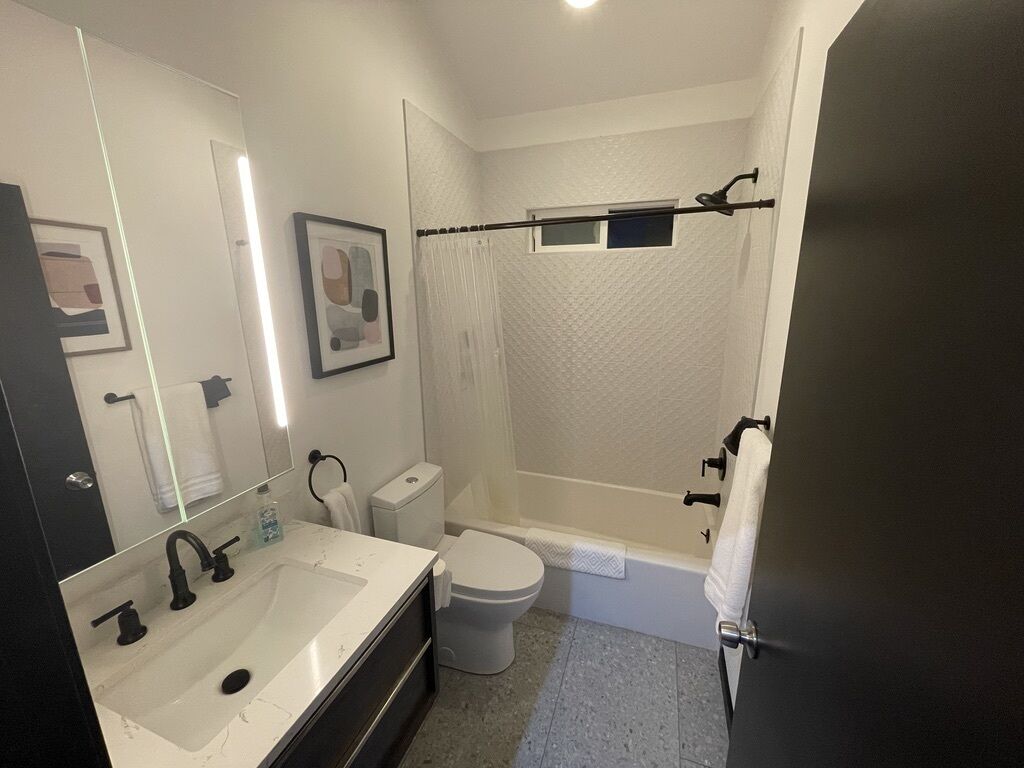 Une salle de bain moderne avec un lavabo, des toilettes et une baignoire, le tout de couleur blanche.