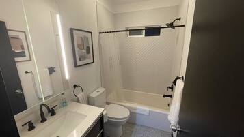 Une salle de bain moderne avec un lavabo, des toilettes et une baignoire, le tout de couleur blanche.