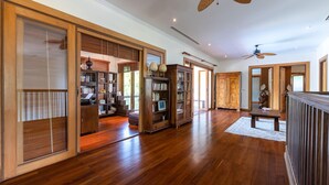 Una habitación amplia con suelo de madera, estanterías empotradas y ventilador de techo.