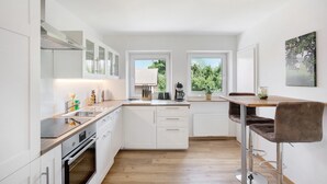Una cocina moderna con armarios blancos, encimera de madera y un taburete de bar.
