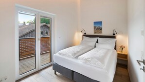 Een slaapkamer met een bed, een nachtkastje, een wandlamp en een schuifdeur naar een buitenruimte.