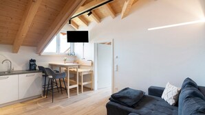 Een moderne keuken met een eethoek, een bank en een aan de muur bevestigde televisie.