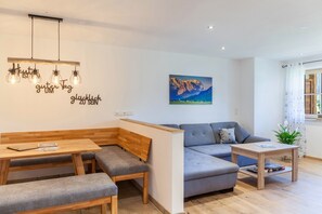 A modern living room with a sofa, a wooden bench, a small table, and a wall-mounted light fixture.