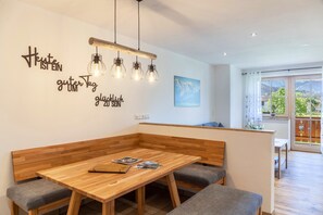 A modern dining area with a wooden table and bench seating, a wall with motivational text, and a view of the outdoors through large windows.