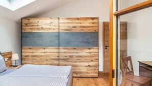 A bedroom with a bed, a nightstand, a lamp, a wooden wardrobe, and a glass door leading to a balcony. - Apartment 'Ferienwohnung Vrenal' with Mountain View, Shared Garden and Wi-Fi (Farchant)
