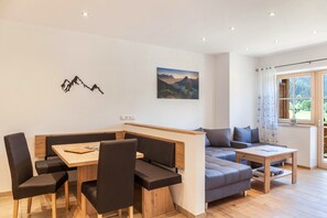 Una sala de estar moderna con comedor, un sofá, una mesa de centro y vistas al exterior a través de un ventanal.