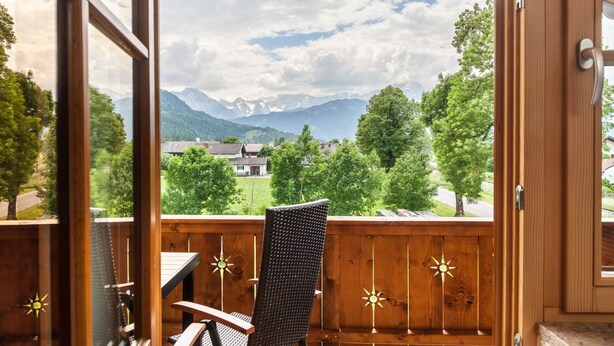 A balcony with a view of mountains, a chair, and a table. - Apartment 'Ferienwohnung Vrenal' with Mountain View, Shared Garden and Wi-Fi (Farchant)