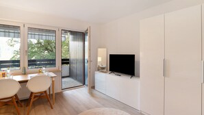 Un salon moderne comprenant un coin repas, un téléviseur et une porte-fenêtre coulissante donnant sur un espace extérieur.