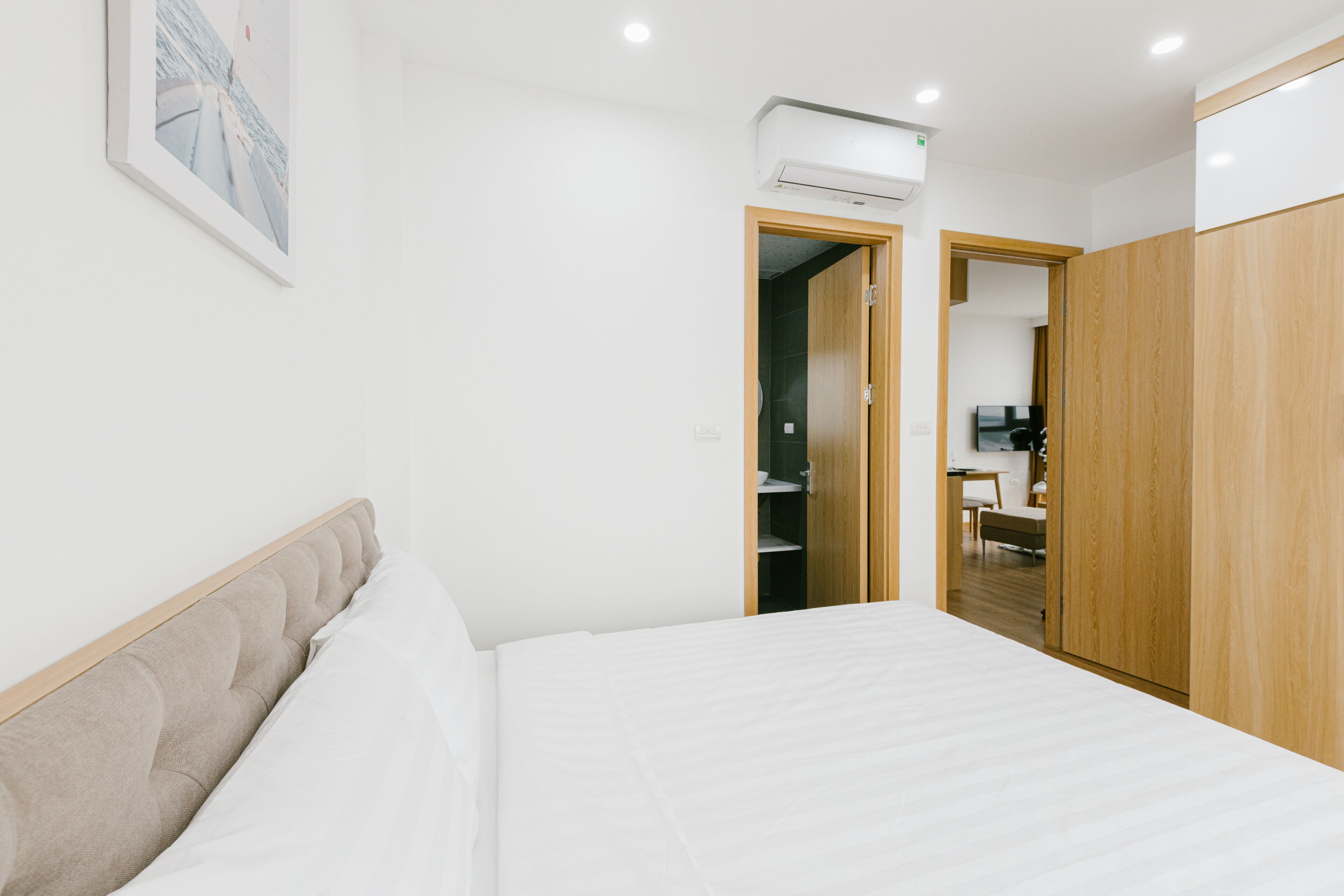 A modern bedroom with a bed, a wardrobe, and a bathroom visible through an open door.
