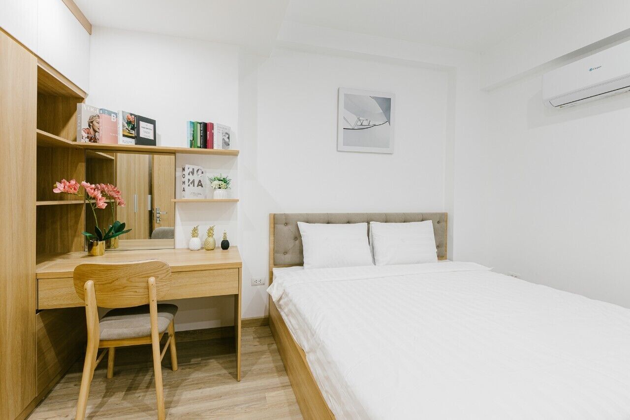 Une chambre à coucher comprenant un lit, un bureau avec une chaise, une bibliothèque et un climatiseur fixé au mur.