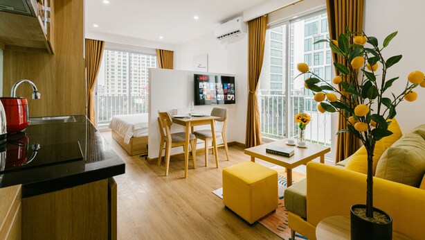 A modern hotel room with a kitchen area, a dining table, a sofa, and a TV. - The Euphoria Hanoi (Hanoi)
