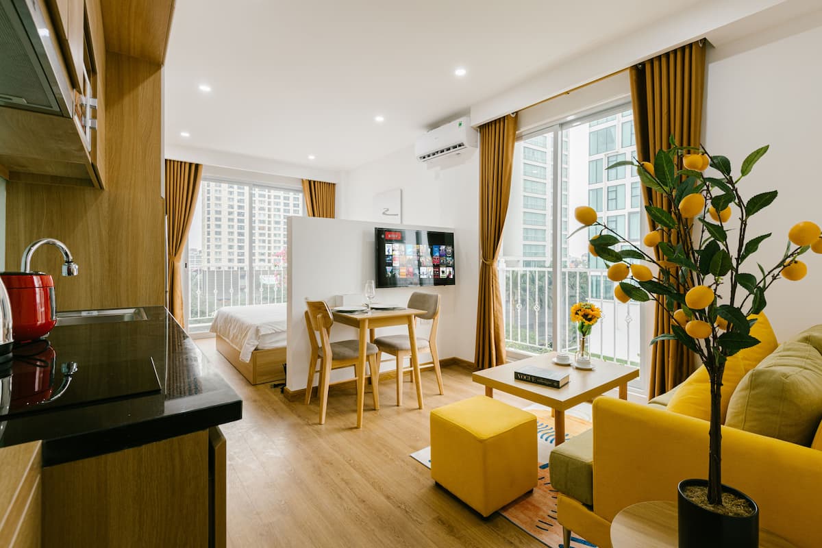 Ein modernes Hotelzimmer mit Küchenzeile, einem Esstisch, einer Couch und einem Fernseher.