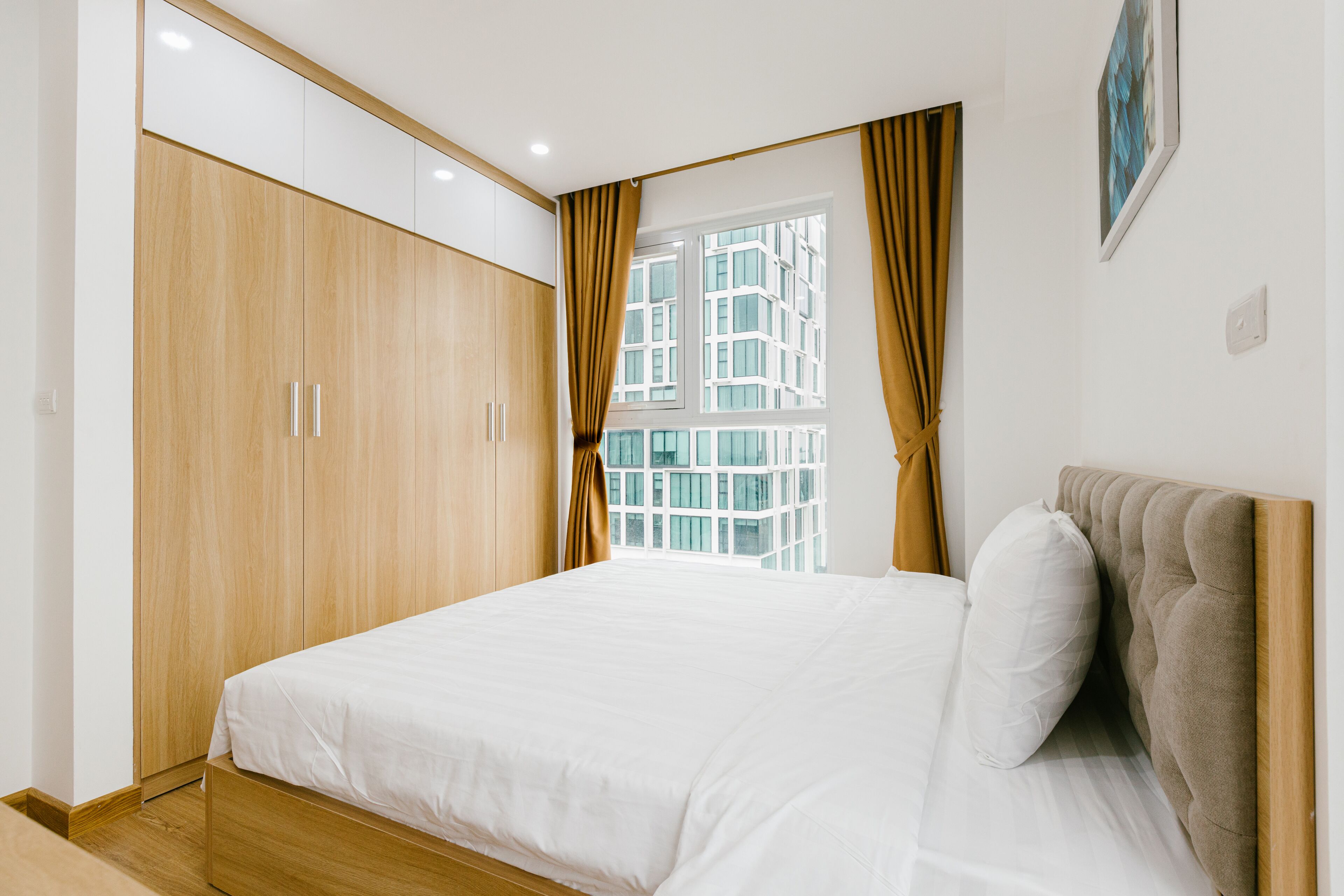 Un dormitorio con cama, armario de madera y ventana con cortinas.