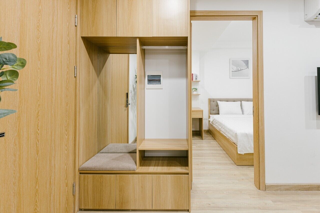 A bedroom with a bed, bedside table, and a wooden wardrobe with a bench.