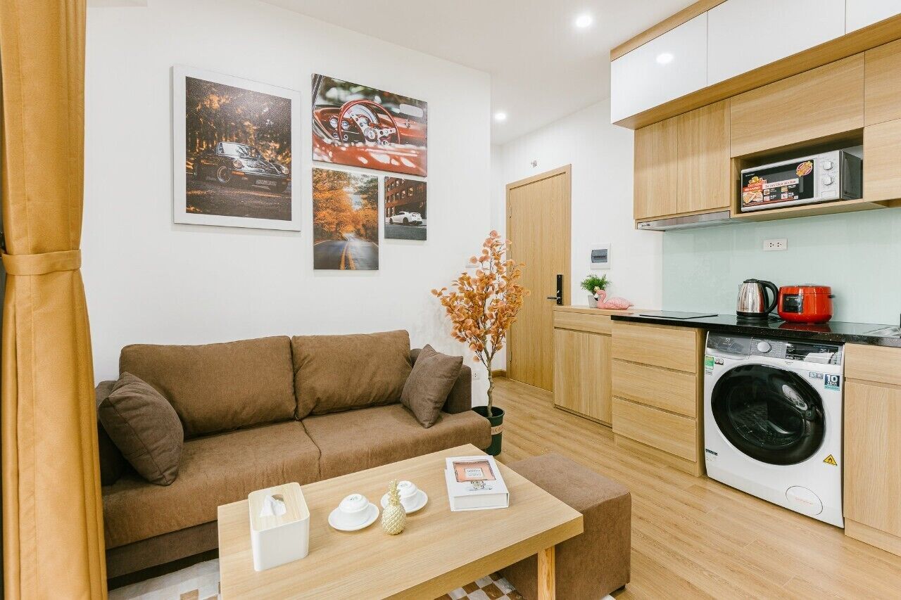 Espaço compacto com sofá, mesa com objetos, máquina de lavar e micro-ondas.
