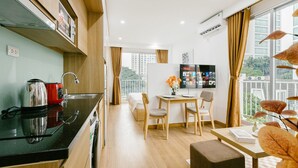 A modern kitchen with a coffee maker, a dining area with a table and chairs, and a TV on the wall. - The Euphoria Hanoi (Hanoi)
