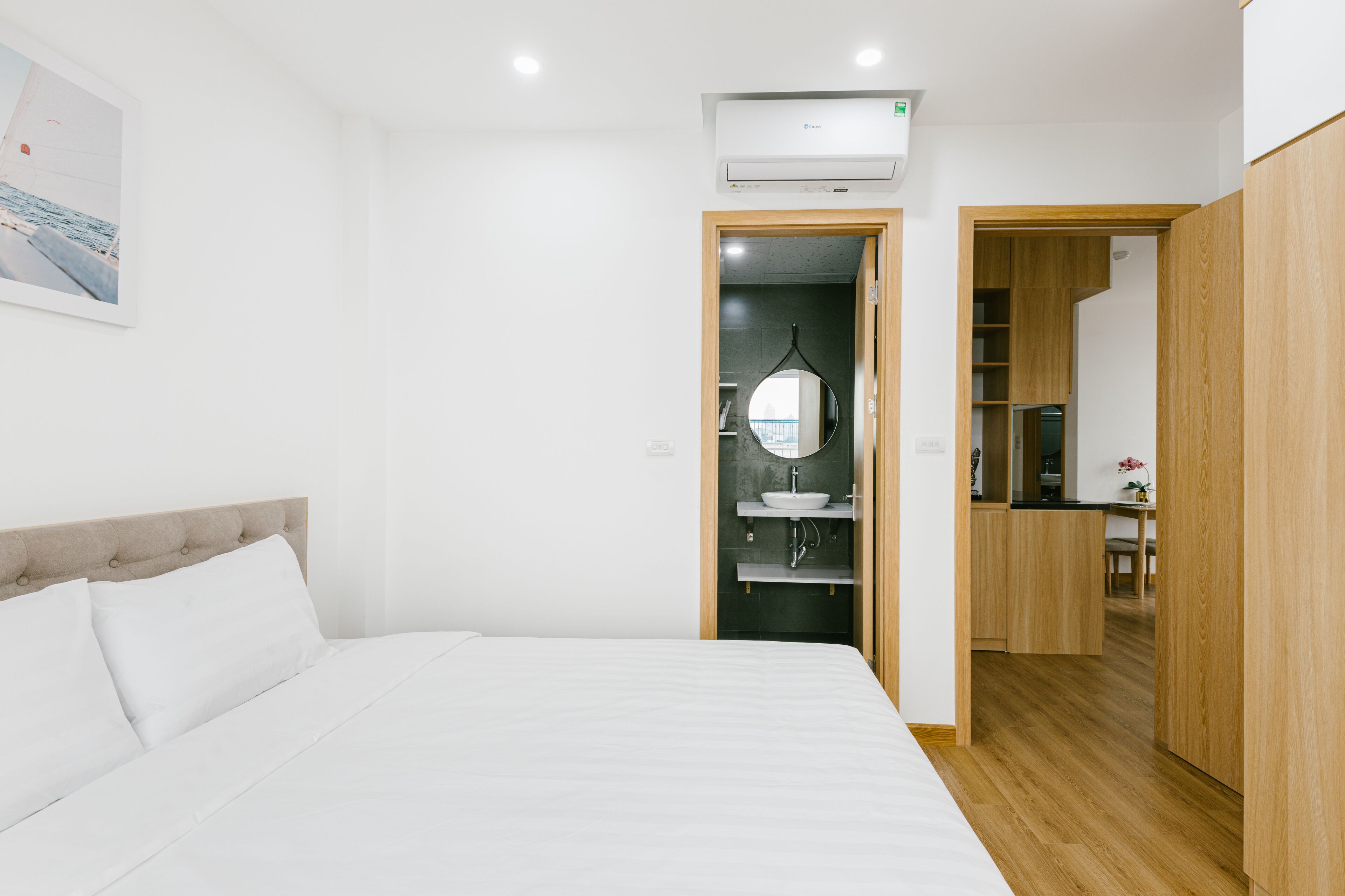 A bedroom with a bed, a bathroom with a mirror, and a wooden wardrobe.
