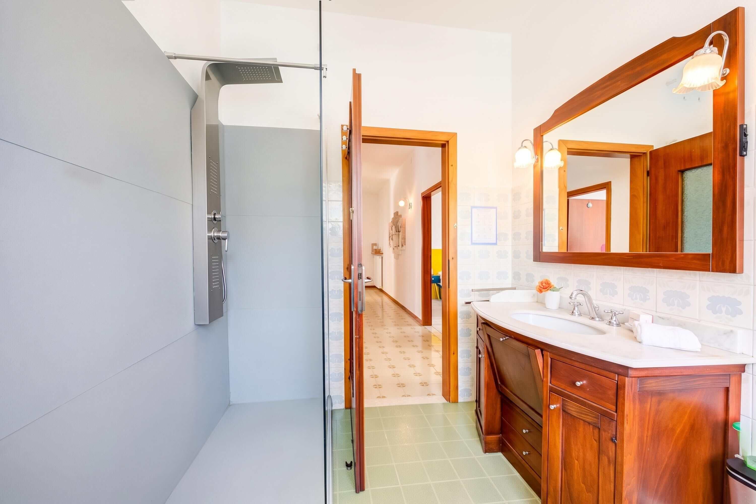Une salle de bain moderne avec une douche à parois de verre, un meuble-lavabo en bois et un grand miroir.