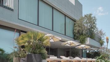 A modern building with a pool area, outdoor seating, and potted plants.