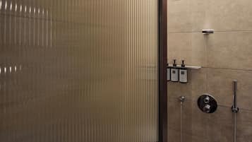 A modern bathroom with a glass partition, a round showerhead, and a wall-mounted faucet.