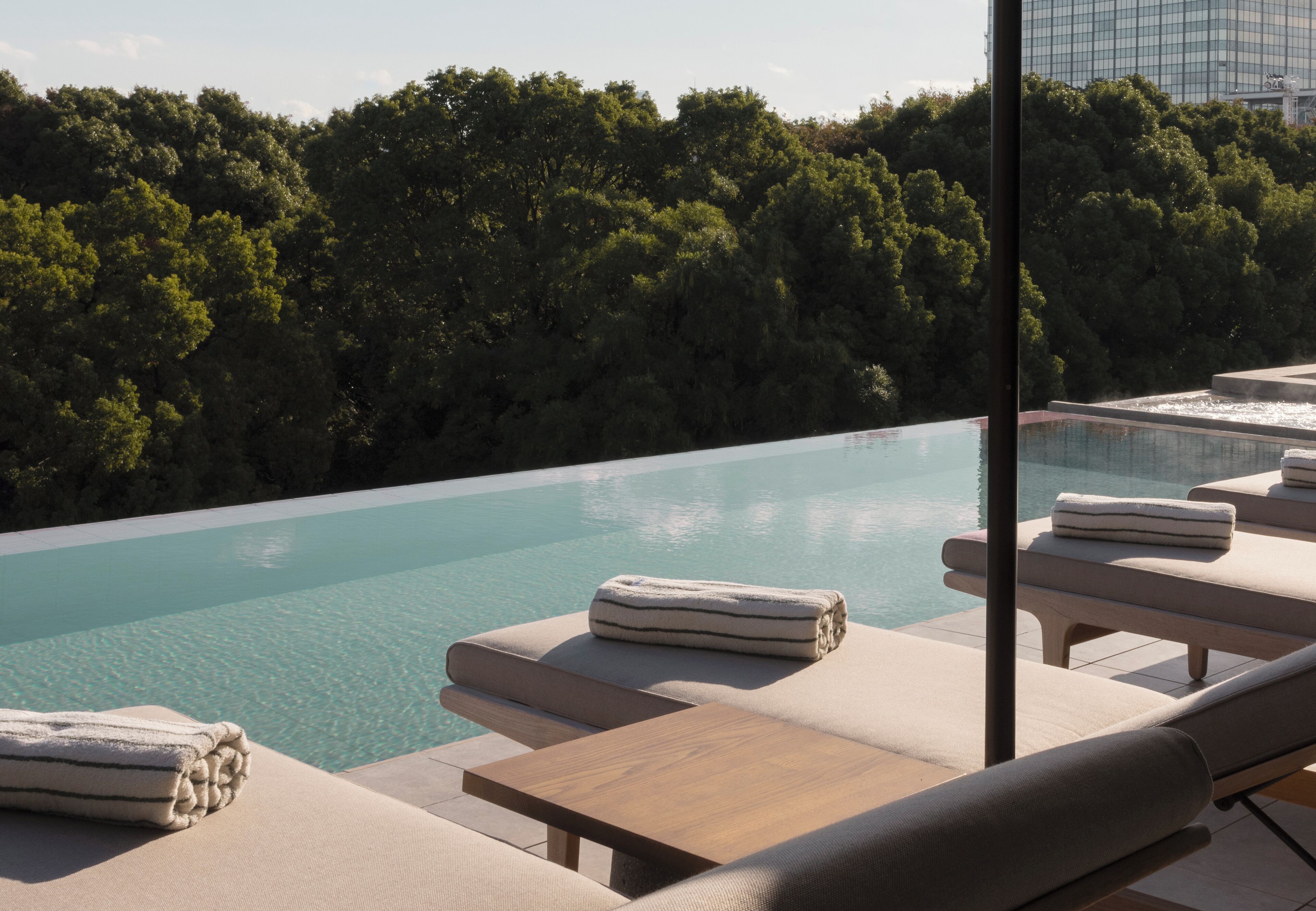 Un espace aménagé au bord de la piscine, avec des chaises longues et des serviettes, entouré d’une végétation luxuriante et donnant sur une piscine aux eaux cristallines.