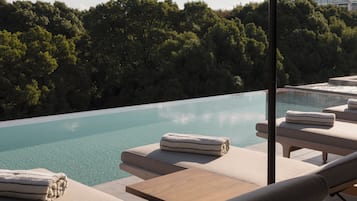 Un espace aménagé au bord de la piscine, avec des chaises longues et des serviettes, entouré d’une végétation luxuriante et donnant sur une piscine aux eaux cristallines.