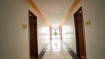 A hallway with doors numbered 409 and 408, leading to a bright room with a plant.