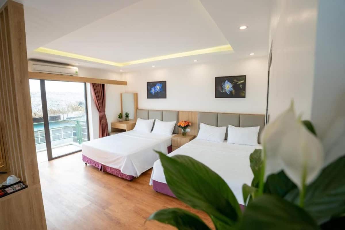 Une chambre d’hôtel avec deux lits, une grande fenêtre, un balcon et un design moderne.