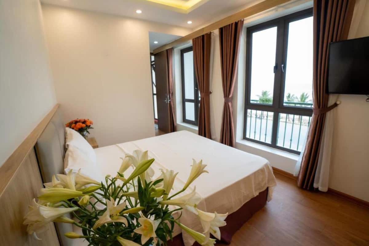 Une chambre d’hôtel avec un lit, un téléviseur fixé au mur et une fenêtre avec des rideaux.