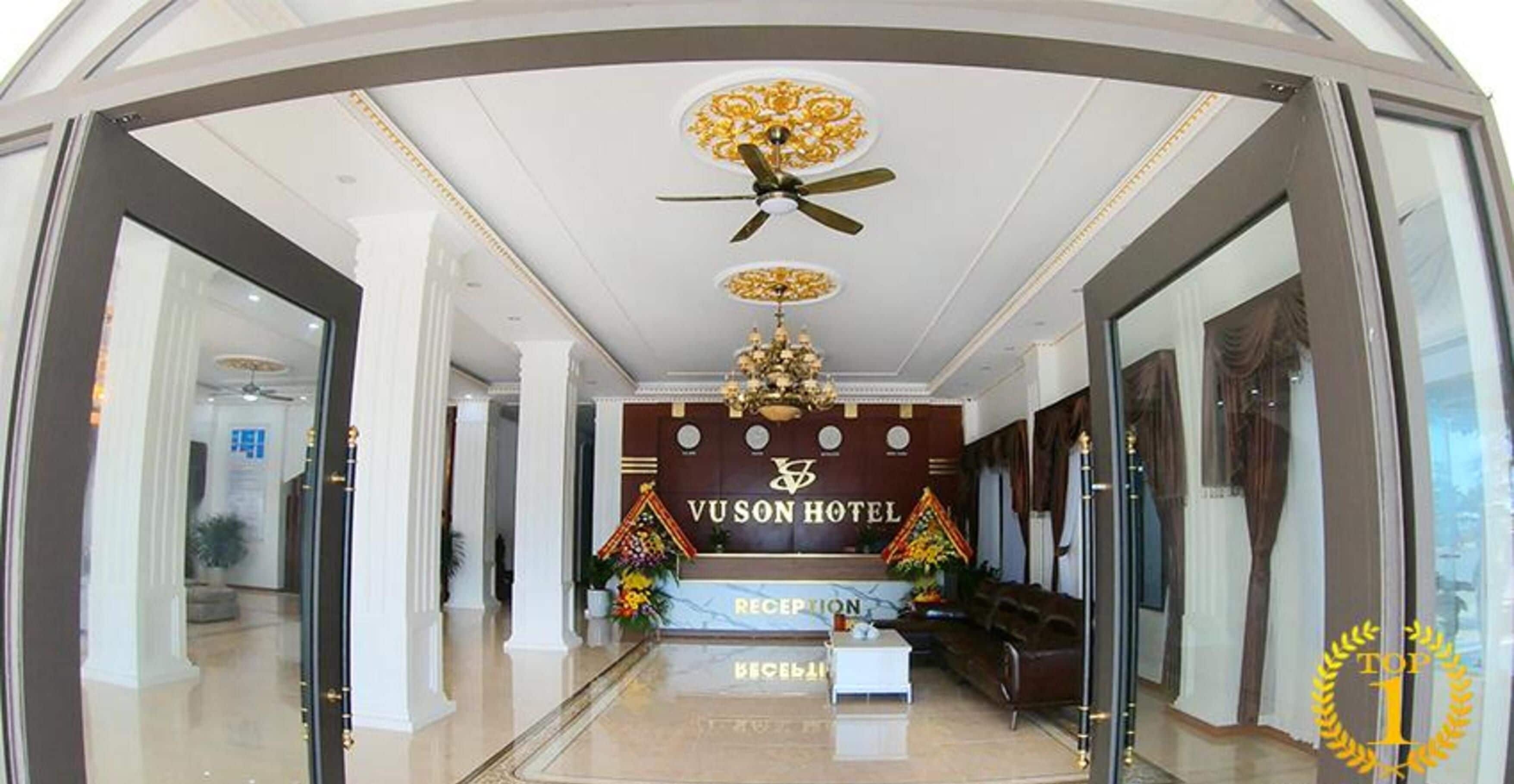 A reception area with a chandelier, a reception desk, and a sign for VUSON HOTEL.
