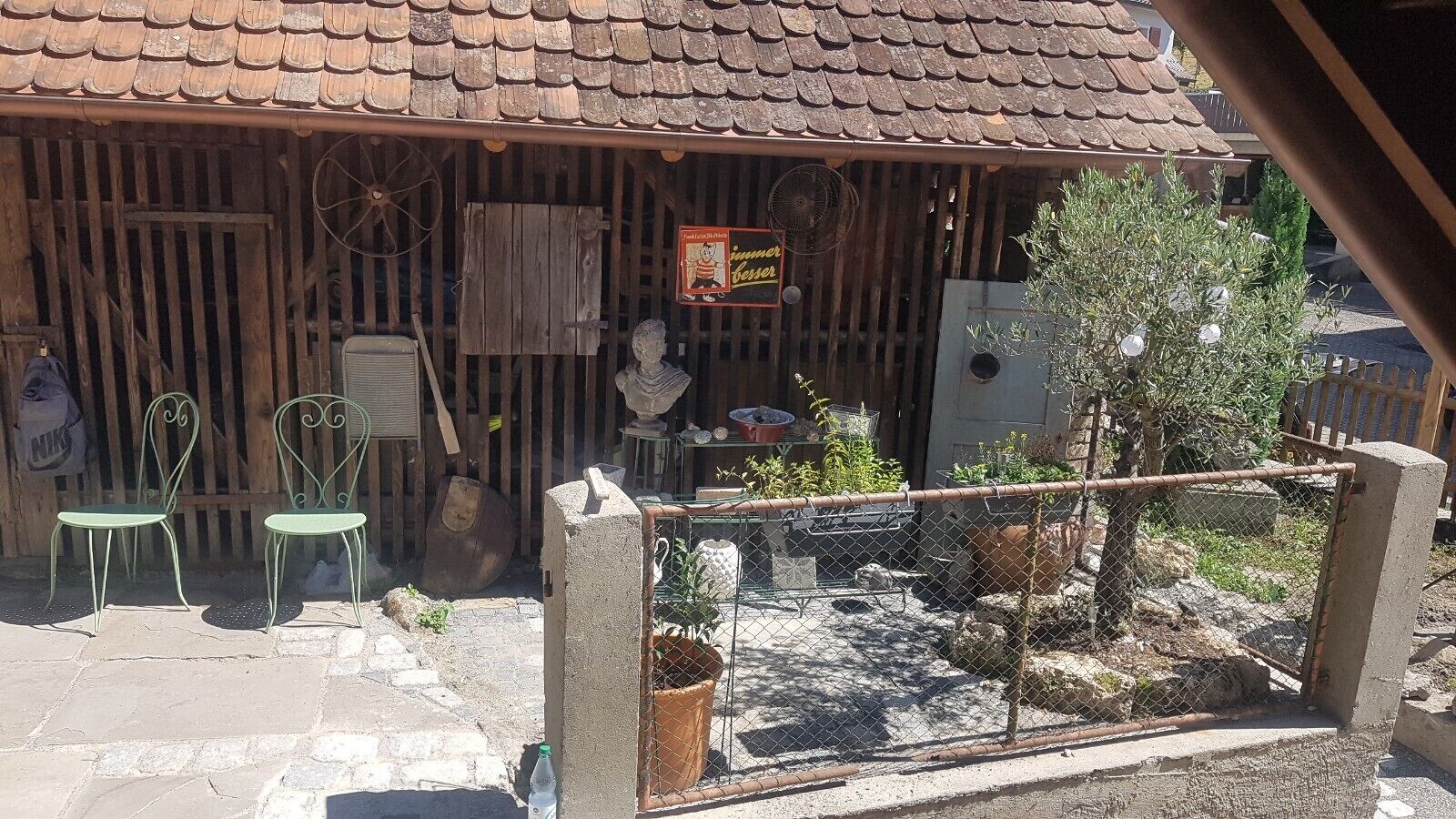A rustic outdoor seating area with wooden chairs and a small garden.