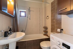 Une salle de bain équipée d’une baignoire, de toilettes, d’un lavabo et d’un lave-linge.