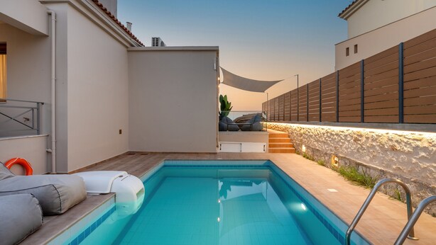 A swimming pool with a sun lounger and a stone wall.